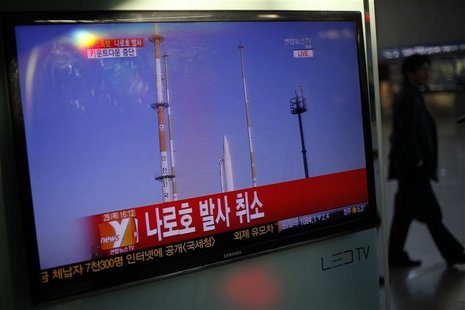 A passenger walks past a TV screen broadcasting the news that the launch of Korea Space Launch Vehicle-1 (KSLV-1), or Naro, was cancelled du A passenger walks past a TV screen broadcasting the news that the launch of Korea Space Launch Vehicle-1 (KSLV-1), or Naro, was cancelled du
