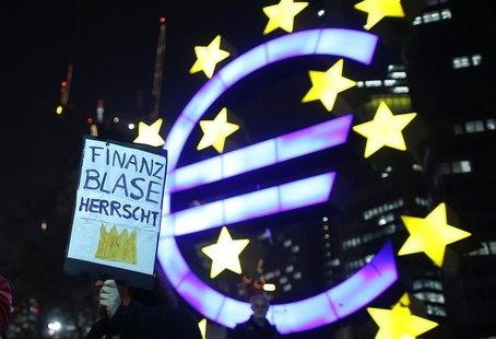 A woman holds a sign in front of the Euro currency sign next to the European Central Bank (ECB) headquarters during a demonstration against A woman holds a sign in front of the Euro currency sign next to the European Central Bank (ECB) headquarters during a demonstration against