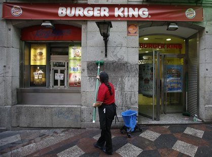 A woman cleans graffiti reading "Exploiters" from the wall of a Burger King restaurant in downtown Madrid November 15, 2012. REUTERS/Andrea A woman cleans graffiti reading "Exploiters" from the wall of a Burger King restaurant in downtown Madrid November 15, 2012. REUTERS/Andrea