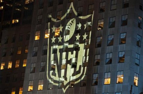 A man stands at a window lit by the NFL logo as he watches performances during the 2012 NFL kickoff show in New York September 5, 2012. REUT A man stands at a window lit by the NFL logo as he watches performances during the 2012 NFL kickoff show in New York September 5, 2012. REUT