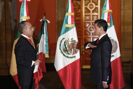 Mexico's outgoing President Felipe Calderon (L) holds the national flag as Mexico's new President Enrique Pena Nieto salutes during a midnig Mexico's outgoing President Felipe Calderon (L) holds the national flag as Mexico's new President Enrique Pena Nieto salutes during a midnig