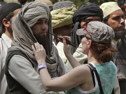 A crew member of Oscar-winning director Kathryn Bigelow's team for the movie "Zero Dark Thirty" applies makeup on an actor during a shoot at A crew member of Oscar-winning director Kathryn Bigelow's team for the movie "Zero Dark Thirty" applies makeup on an actor during a shoot at