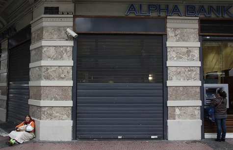 A woman makes a transaction at the automated teller machine (ATM) as another begs outside an Alpha bank branch in central Athens November 29 A woman makes a transaction at the automated teller machine (ATM) as another begs outside an Alpha bank branch in central Athens November 29