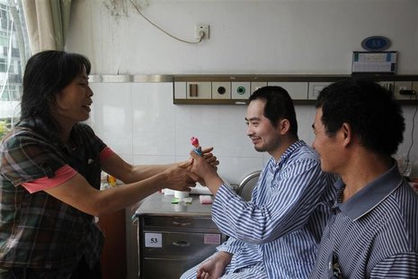 Zhang Tingzhen (C) is given a doll to play with by his mother Wei Xiuying while sitting beside his father Zhang Guangde at a Shenzhen hospit Zhang Tingzhen (C) is given a doll to play with by his mother Wei Xiuying while sitting beside his father Zhang Guangde at a Shenzhen hospit