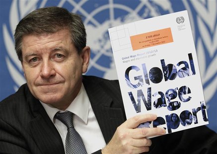 Guy Ryder, Director-General of the International Labor Organization (ILO) poses with a copy of the Global Wage Report after a news conferenc Guy Ryder, Director-General of the International Labor Organization (ILO) poses with a copy of the Global Wage Report after a news conferenc