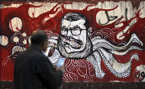A man take a picture of a mural of Egypt's President Mohamed Mursi and with Arabic words that reads "Leave" on the wall of the presidential A man take a picture of a mural of Egypt's President Mohamed Mursi and with Arabic words that reads "Leave" on the wall of the presidential