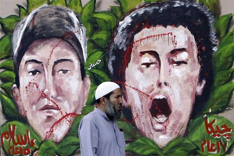 An anti-Mursi protester walks past graffiti depicting two activists who died recently, at Tahrir Square in Cairo December 10, 2012. REUTERS/ An anti-Mursi protester walks past graffiti depicting two activists who died recently, at Tahrir Square in Cairo December 10, 2012. REUTERS/