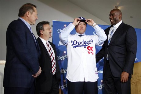 Los Angeles Dodgers' new left-handed pitcher Hyun-Jin Ryu of South Korea (2nd R) wears a cap as he puts on his new jersey while standing wit Los Angeles Dodgers' new left-handed pitcher Hyun-Jin Ryu of South Korea (2nd R) wears a cap as he puts on his new jersey while standing wit