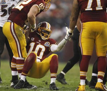 Washington Redskins quarterback Robert Griffin III (C) is helped up by teammates after being tackled by the Baltimore Ravens defense in the Washington Redskins quarterback Robert Griffin III (C) is helped up by teammates after being tackled by the Baltimore Ravens defense in the