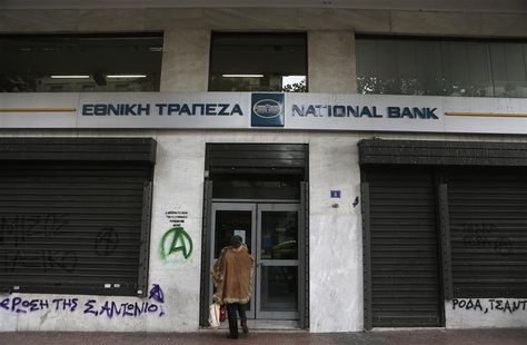 A woman stands outside a National bank branch in central Athens December 11, 2012. REUTERS/John Kolesidis A woman stands outside a National bank branch in central Athens December 11, 2012. REUTERS/John Kolesidis