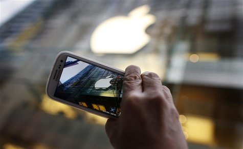 A passerby photographs an Apple store logo with his Samsung Galaxy phone on the morning iPhone 5 goes on sale to the public in central Sydne A passerby photographs an Apple store logo with his Samsung Galaxy phone on the morning iPhone 5 goes on sale to the public in central Sydne