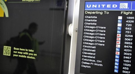 A customer is reflected in a screen showing the schedule times of United Continental Holdings Inc flights at Newark International airport in A customer is reflected in a screen showing the schedule times of United Continental Holdings Inc flights at Newark International airport in