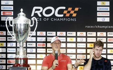Driver Michael Schumacher (L) from Team Germany speaks during a news conference for the Race of Champions, as Sebastian Vettel listens, at t Driver Michael Schumacher (L) from Team Germany speaks during a news conference for the Race of Champions, as Sebastian Vettel listens, at t