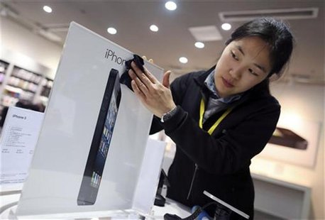 An employee cleans an advertisement plate at an Apple dealership on the eve of iPhone 5's release, in Wuhan, Hubei province December 13, 201 An employee cleans an advertisement plate at an Apple dealership on the eve of iPhone 5's release, in Wuhan, Hubei province December 13, 201