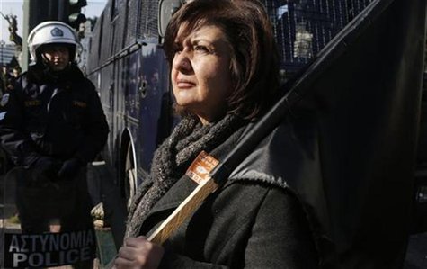 A woman holds a black flag during a rally against state sector layoffs demanded by the country's international lenders, outside the parliame A woman holds a black flag during a rally against state sector layoffs demanded by the country's international lenders, outside the parliame