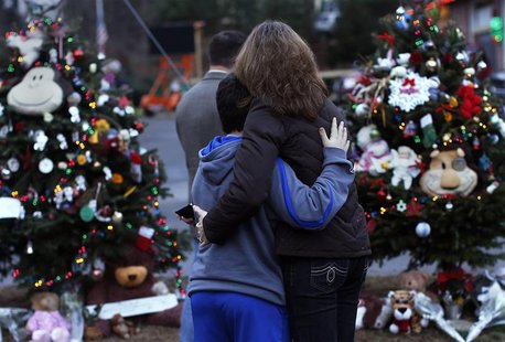 A woman embraces a boy next to a makeshift memorial for victims who died in the December 14 shootings at Sandy Hook Elementary School, in Ne A woman embraces a boy next to a makeshift memorial for victims who died in the December 14 shootings at Sandy Hook Elementary School, in Ne