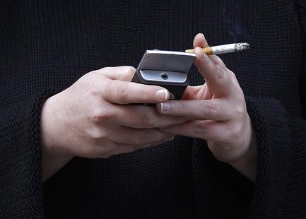 A woman uses her mobile phone while holding a cigarette in central London, February 1, 2010. REUTERS/Suzanne Plunkett A woman uses her mobile phone while holding a cigarette in central London, February 1, 2010. REUTERS/Suzanne Plunkett