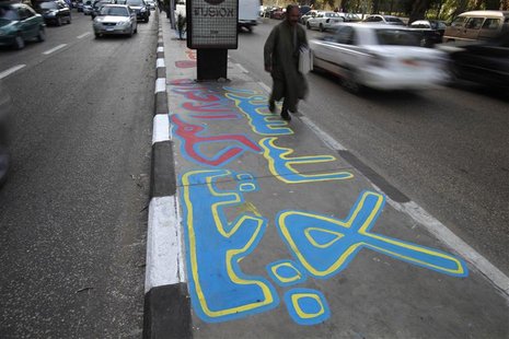 A man walks on a graffiti on a pavement in Cairo December 20, 2012. The graffiti reads, "No to the constitution under the rule of the (Musli
