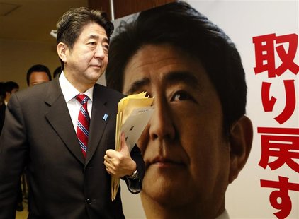 Shinzo Abe, Japan's incoming prime minister and the leader of Liberal Democratic Party (LDP), walks past his portrait after attending a meet Shinzo Abe, Japan's incoming prime minister and the leader of Liberal Democratic Party (LDP), walks past his portrait after attending a meet
