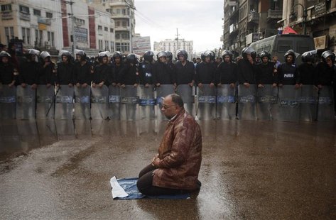A supporter of Egyptian President Mohamed Mursi sits for prayers as riot policemen stand in line to separate pro- and anti-Mursi protesters A supporter of Egyptian President Mohamed Mursi sits for prayers as riot policemen stand in line to separate pro- and anti-Mursi protesters