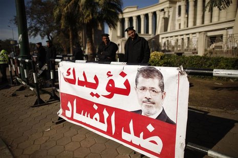 Policemen stand guard near a banner outside the constitutional court put up by supporters of Egyptian President Mohamed Mursi as they stage Policemen stand guard near a banner outside the constitutional court put up by supporters of Egyptian President Mohamed Mursi as they stage