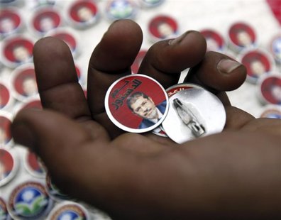 Badges showing an image of Egypt's President Mohamed Mursi and the words "Yes to constitution" are displayed at a street stall outside Al Az Badges showing an image of Egypt's President Mohamed Mursi and the words "Yes to constitution" are displayed at a street stall outside Al Az