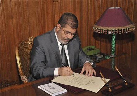 Egypt's President Mohamed Mursi signs a decree to put into effect the new constitution in Cairo December 25, 2012, in this handout photo rel Egypt's President Mohamed Mursi signs a decree to put into effect the new constitution in Cairo December 25, 2012, in this handout photo rel