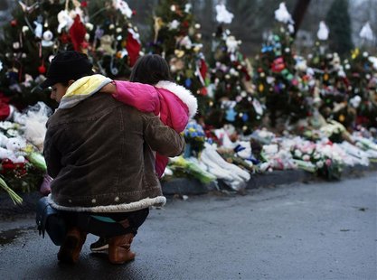 A woman holds a child next to a makeshift memorial for victims who died in the December 14 shootings at Sandy Hook Elementary School, in New A woman holds a child next to a makeshift memorial for victims who died in the December 14 shootings at Sandy Hook Elementary School, in New