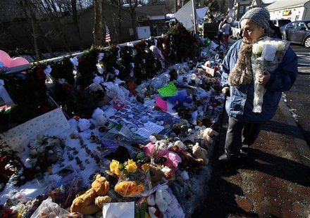 A woman with flowers walks past a makeshift memorial in Sandy Hook, after the December 14 shooting tragedy when a gunman shot dead 20 studen A woman with flowers walks past a makeshift memorial in Sandy Hook, after the December 14 shooting tragedy when a gunman shot dead 20 studen