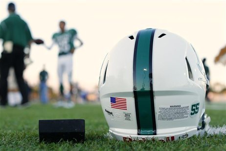 A football helmet's health warning sticker is pictured between a U.S. flag and the number 55, in memory of former student and NFL player Jun A football helmet's health warning sticker is pictured between a U.S. flag and the number 55, in memory of former student and NFL player Jun