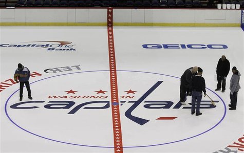 Workers put the finishing touches on the installation of the Washington Capitals logo at center ice during the laying down process of the pl Workers put the finishing touches on the installation of the Washington Capitals logo at center ice during the laying down process of the pl