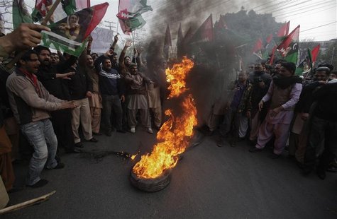 Supporters of Pakistan People's Party (PPP) hold party flags as they burn tyres during a protest against the Supreme Court decision to arres Supporters of Pakistan People's Party (PPP) hold party flags as they burn tyres during a protest against the Supreme Court decision to arres