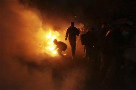 Protesters are seen by firelight as they run from tear gas fired by the military and riot police during clashes along a road which leads to Protesters are seen by firelight as they run from tear gas fired by the military and riot police during clashes along a road which leads to