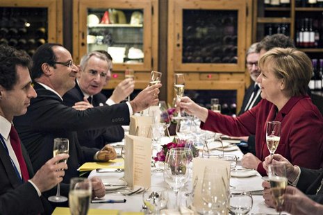 German Chancellor Angela Merkel (R) and French President Francois Hollande salute to each other during a private dinner in a Berlin restaura German Chancellor Angela Merkel (R) and French President Francois Hollande salute to each other during a private dinner in a Berlin restaura