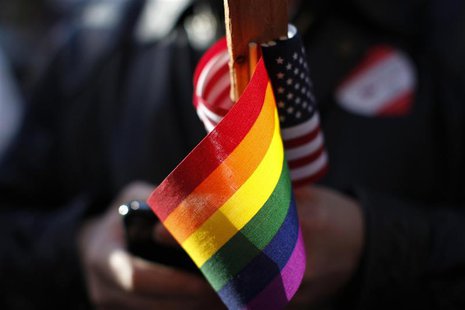 Marriage equality supporter Gus Thompson holds gay pride and American flags at a demonstration outside the appeals hearing on California?s P Marriage equality supporter Gus Thompson holds gay pride and American flags at a demonstration outside the appeals hearing on California?s P