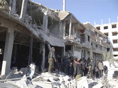 Free Syrian Army fighters and residents are seen near buildings damaged after what activists say were missiles fired by Syrian Air Force fig Free Syrian Army fighters and residents are seen near buildings damaged after what activists say were missiles fired by Syrian Air Force fig