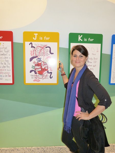 Jess Kelley in front of the Alphabet of Cancer wall.