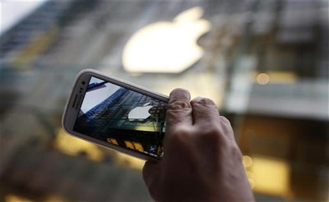 A passerby photographs an Apple store logo with his Samsung Galaxy phone on the morning iPhone 5 goes on sale to the public in central Sydne A passerby photographs an Apple store logo with his Samsung Galaxy phone on the morning iPhone 5 goes on sale to the public in central Sydne