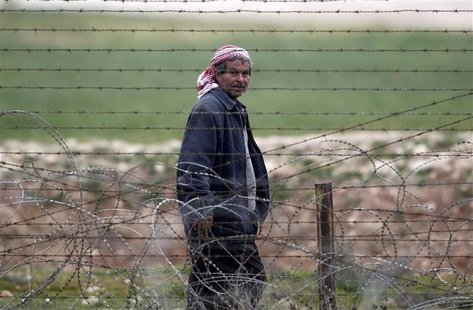 A man from the northern Syrian town of Ras al-Ain walks along the border fence as he is pictured from the Turkish border town of Ceylanpinar A man from the northern Syrian town of Ras al-Ain walks along the border fence as he is pictured from the Turkish border town of Ceylanpinar
