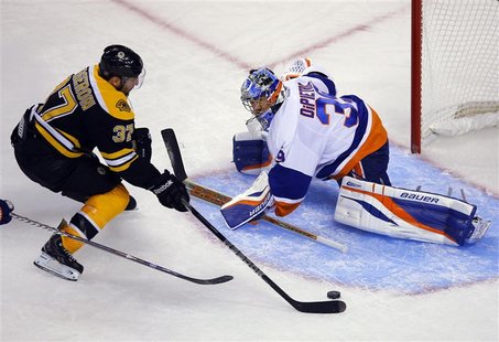Boston Bruins' center Patrice Bergeron (L) scores a goal against New York Islanders' goaltender Rick DiPietro in the third period of their N Boston Bruins' center Patrice Bergeron (L) scores a goal against New York Islanders' goaltender Rick DiPietro in the third period of their N
