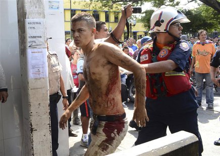 A rescue worker walks with an unidentified injured man during an uprising at the Centro Occidental (Uribana) prison in Barquisimeto in this A rescue worker walks with an unidentified injured man during an uprising at the Centro Occidental (Uribana) prison in Barquisimeto in this