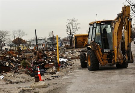 A vehicle makes its way near homes devastated by fire and the effects of Hurricane Sandy in the Breezy Point section of the Queens borough i A vehicle makes its way near homes devastated by fire and the effects of Hurricane Sandy in the Breezy Point section of the Queens borough i