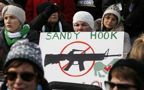 People hold signs memorializing Sandy Hook Elementary School, where 26 children and adults were killed in a mass shooting in December, as th People hold signs memorializing Sandy Hook Elementary School, where 26 children and adults were killed in a mass shooting in December, as th