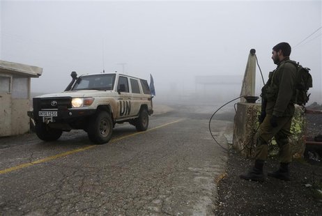 An Israeli soldier looks on as a United Nations jeep drives past the Quneitra border crossing between Israel and Syria, in the Golan Heights An Israeli soldier looks on as a United Nations jeep drives past the Quneitra border crossing between Israel and Syria, in the Golan Heights