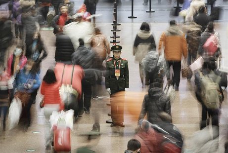 A paramilitary policeman (C) stands guard as passengers walk to board their trains at the Beijing West Railway Station January 31, 2013. REU A paramilitary policeman (C) stands guard as passengers walk to board their trains at the Beijing West Railway Station January 31, 2013. REU