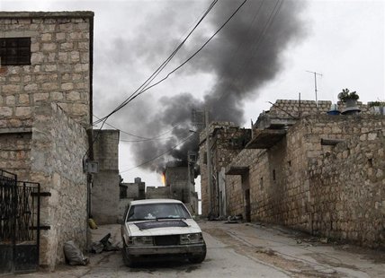 Smoke rises behind a car decorated with an Islamist flag in the Sheikh Saeed district, near a cement factory in Aleppo, February 7, 2013. RE Smoke rises behind a car decorated with an Islamist flag in the Sheikh Saeed district, near a cement factory in Aleppo, February 7, 2013. RE