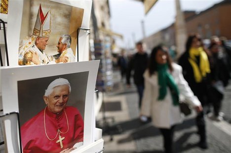 Tourists walk past pictures of Pope Benedict XVI displayed in a shop in Rome February 12, 2013.Pope Benedict stunned the Roman Catholic Chur Tourists walk past pictures of Pope Benedict XVI displayed in a shop in Rome February 12, 2013.Pope Benedict stunned the Roman Catholic Chur
