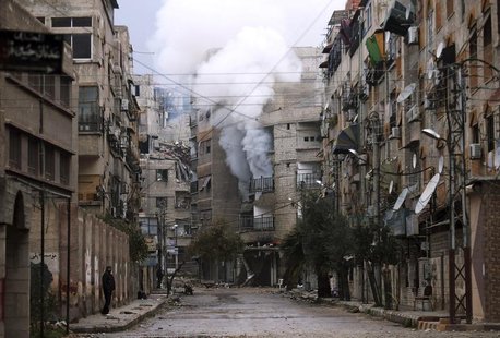 A man stands in an empty street near a burning building hit by a mortar shell fired by Syrian Army soldiers, in the Zamalka neighbourhood of A man stands in an empty street near a burning building hit by a mortar shell fired by Syrian Army soldiers, in the Zamalka neighbourhood of