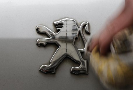 A man cleans a company logo on a Peugeot car parked in Paris, February 12, 2013. REUTERS/Christian Hartmann A man cleans a company logo on a Peugeot car parked in Paris, February 12, 2013. REUTERS/Christian Hartmann