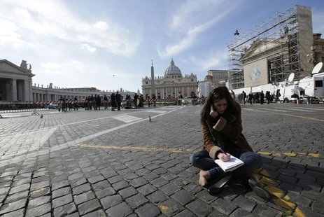 A media correspondent sits on the ground in Rome, as Saint Peter's Basilica at the Vatican is seen in the background, February 13, 2013. REU A media correspondent sits on the ground in Rome, as Saint Peter's Basilica at the Vatican is seen in the background, February 13, 2013. REU